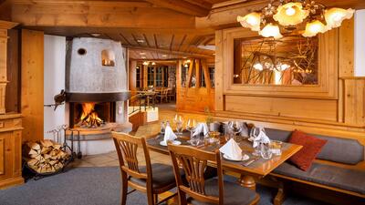 In Wildhaus (9658, Kanton St. Gallen) zeigt die Hirschen Stube Gourmet & Beiz einen gemuetlichen Gastraum mit Kaminfeuer, Holzeinrichtung und festlich gedeckten Tischen.