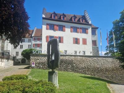 In Arbon (9320, Kanton Thurgau) erhebt sich das historische Schloss Arbon mit weisser Fassade und roten Fensterlaeden, heute Sitz des Historischen Museums.