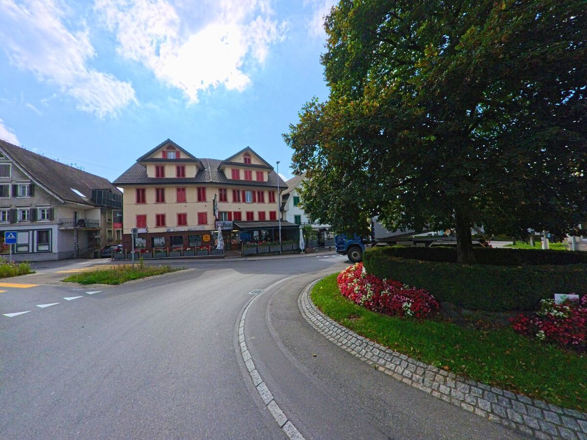Rund um einen begrünten Kreisel verlaufen Strassen und Gebäude im Zentrum von Hochdorf (6280, Kanton Luzern).