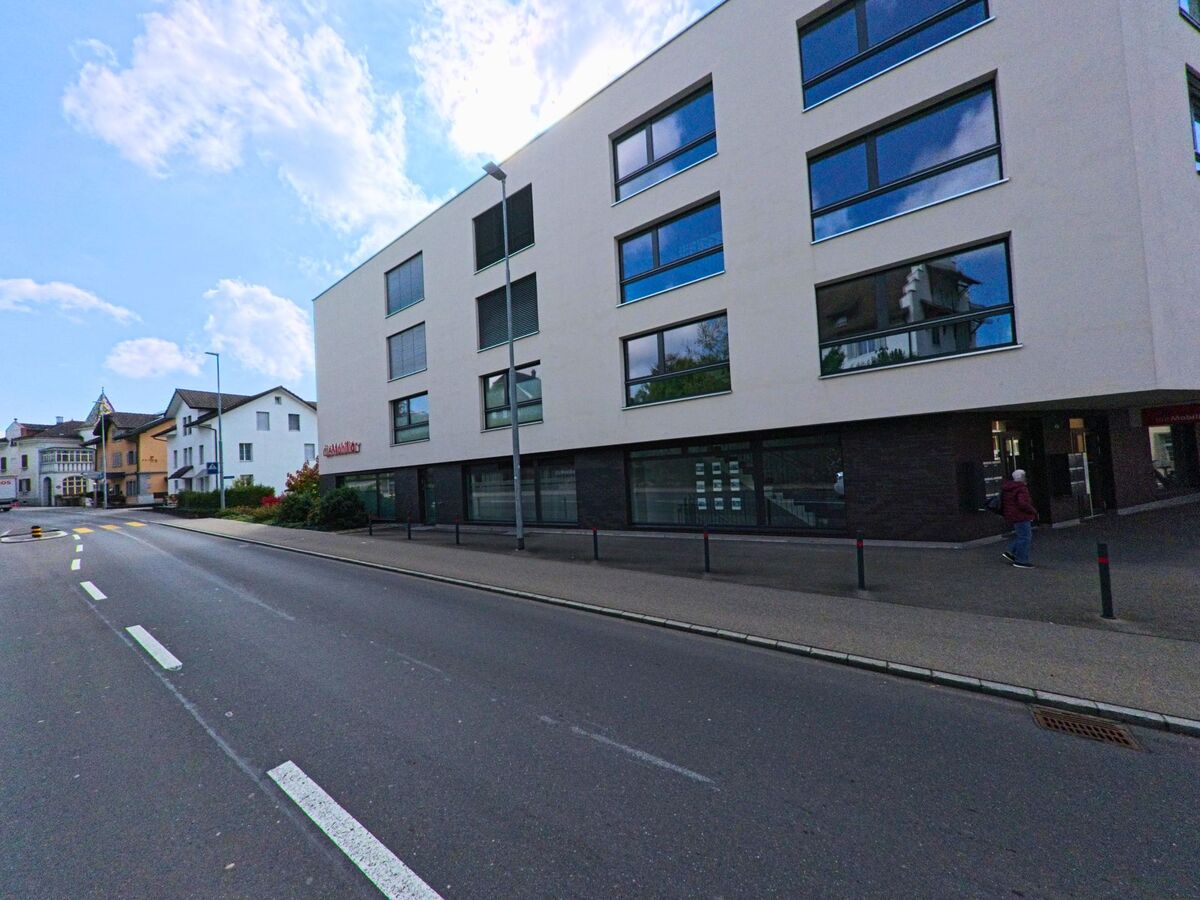 Ein modernes Mehrfamilienhaus prägt das Strassenbild von Hochdorf (6280, Kanton Luzern) bei klarem Himmel.
