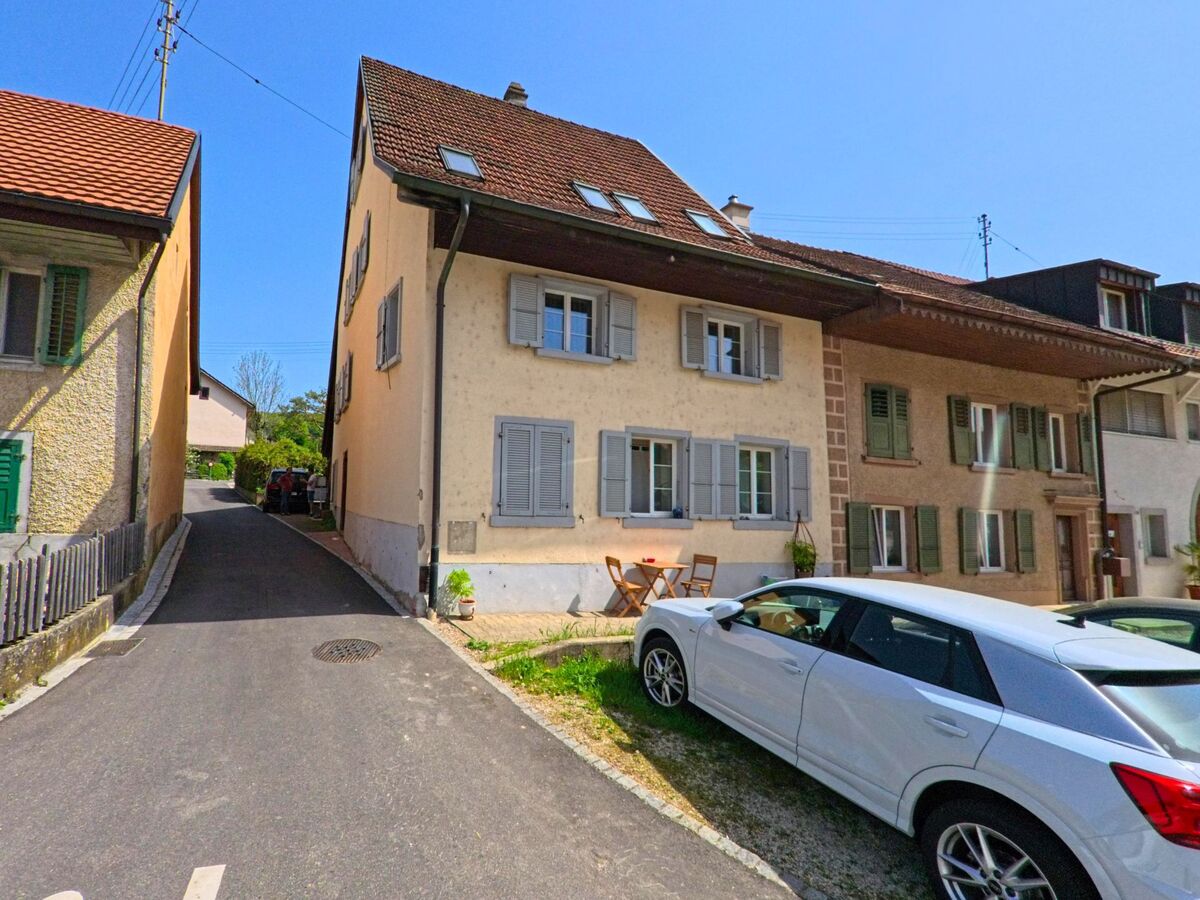 In einer engen Gasse von Hochwald (4146, Kanton Solothurn) stehen historische Wohnhaeuser mit Fensterlaeden und kleinen Sitzplaetzen vor dem Eingang.