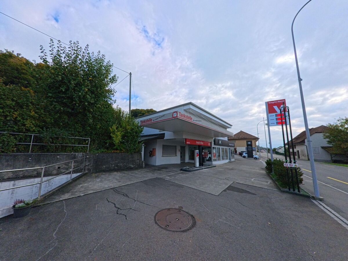 Die Tankstelle Voegeli-Meyer in Holderbank (5113, Kanton Aargau) liegt an der Hauptstrasse und wird von Wohnhaeusern und Wald begrenzt.