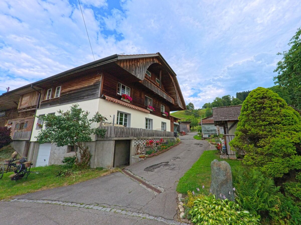 In Homberg (3622, Kanton Bern) fuehrt ein schmaler geteerte Weg zwischen traditionellen Wohnhaeusern mit Blumenschmuck und liebevoll gepflegten Gaerten den Hang hinauf.