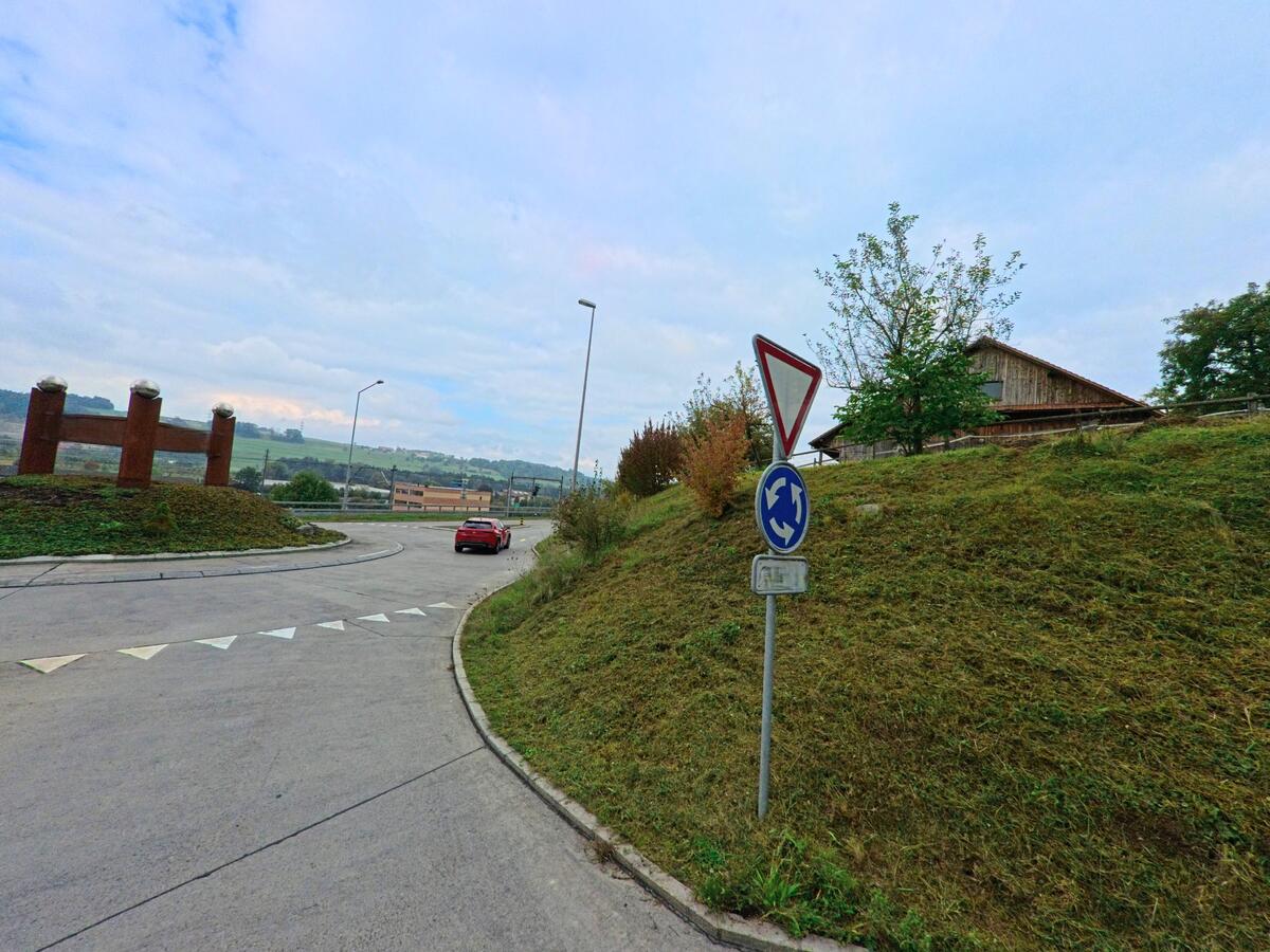 Am Rand der Fahrbahn markiert ein kleiner Kreisverkehr die Verkehrsführung in Honau (6038, Kanton Luzern).