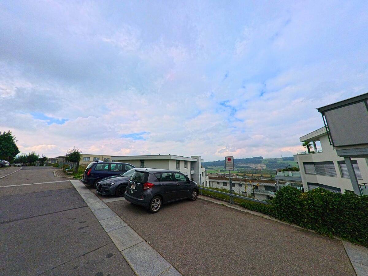 Neben Wohngebäuden befindet sich ein offener Parkplatz im Siedlungsgebiet von Honau (6038, Kanton Luzern).