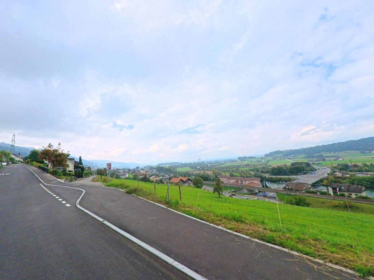 Entlang einer Strasse öffnet sich der Blick über Felder und das Tal von Honau (6038, Kanton Luzern).