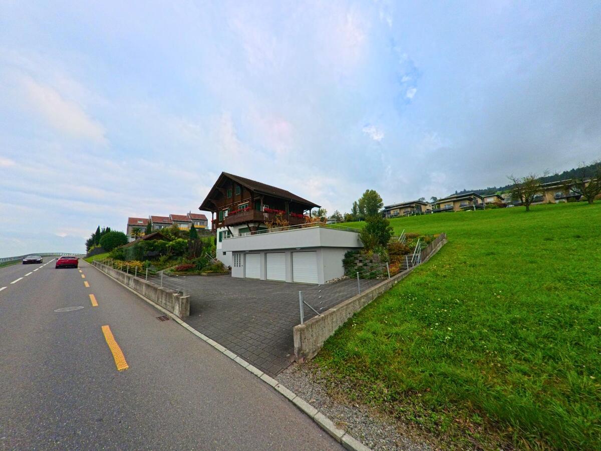 Ein traditionelles Wohnhaus mit Vorplatz steht leicht erhöht in Honau (6038, Kanton Luzern).