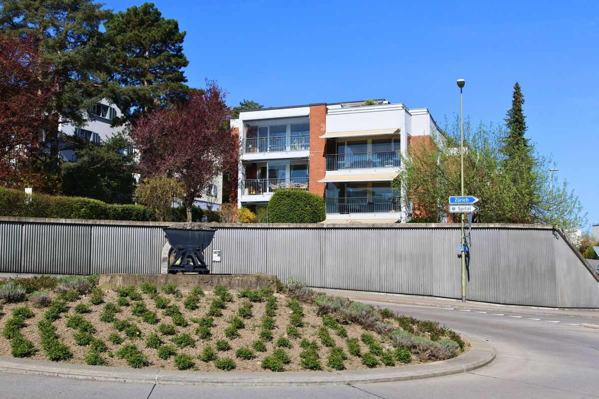  Ein Kreisverkehr mit einem alten Förderwagen als Denkmal liegt in Horgen (8810, Kanton Zürich) vor modernen Wohnbauten und Wegweisern Richtung Zürich und Spital.