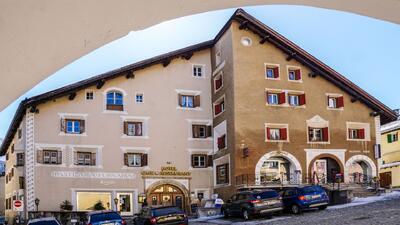 Das Hotel Klarer in Zuoz (7524, Kanton Graubuenden) praesentationiert sich mit historischer Fassade, roten Fensterlaeden und angrenzendem Cafe-Restaurant.