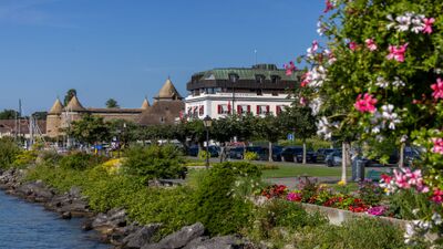 Das Hôtel Mont-Blanc Au Lac in Morges (1110, Kanton Waadt) liegt malerisch am Seeufer, umgeben von bunten Blumen, Bäumen und mit Blick auf das historische Schloss von Morges.