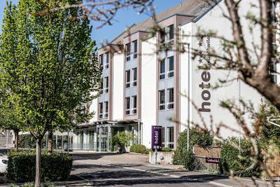 In Muenchwilen (9542, Kanton Thurgau) steht das Hotel Muenchwilen mit moderner Fassade und grossen Fenstern an einer von Baeumen gesaeumten Strasse.