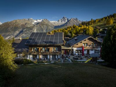 Das Hotel Restaurant Bürchnerhof in Bürchen (3935, Kanton Wallis) liegt vor einer eindrucksvollen Bergkulisse und besitzt eine grosse Terrasse sowie Solarpaneele auf dem Dach.
