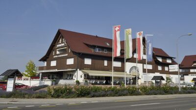 In Guettingen (8594, Kanton Thurgau) steht das Hotel Restaurant Seemoewe AG mit traditioneller Holzfassade, grossen Flaggen und Terrasse an der Hauptstrasse.