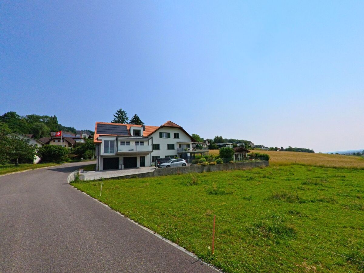 Am Ortsrand von Hubersdorf (4535, Kanton Solothurn) stehen moderne Wohnhaeuser mit Gaerten vor offenen Feldern.