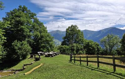 Eine gruene Wiese mit Sitzbaenken und Spielbereich liegt mit Blick auf Berge in Praez (7424, Kanton Graubuenden) und zeigt Natur und Erholung.