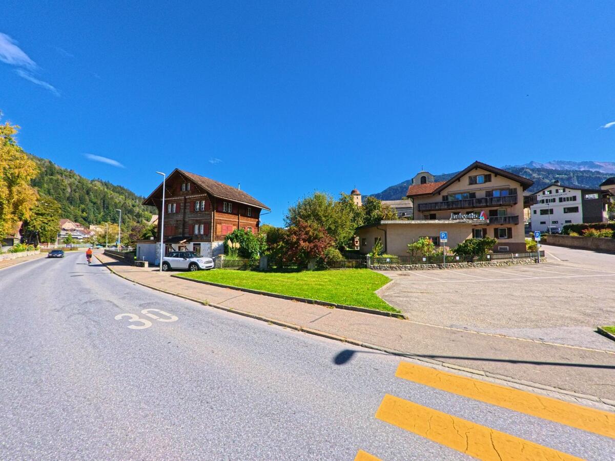 Am Ortseingang von Ilanz (7130, Kanton Graubünden) stehen traditionelle Holzhäuser und moderne Wohnbauten vor der Kulisse der umliegenden Berge.