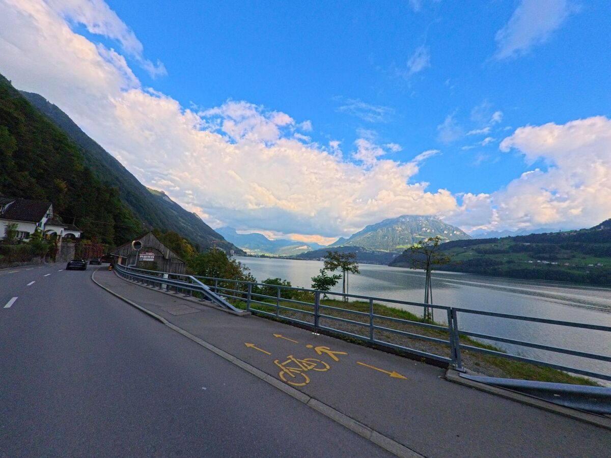 Entlang einer Uferstrasse öffnet sich der Blick auf den See und die Berge bei Ingenbohl (6440, Kanton Schwyz).