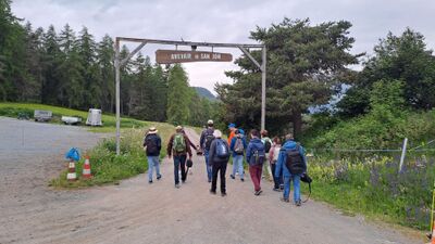 Mitglieder von Insieme Bezirk Horgen (8810, Kanton Zürich) wandern in einer Gruppe auf einem Weg durch eine grüne Landschaft mit Wäldern und Bergen.