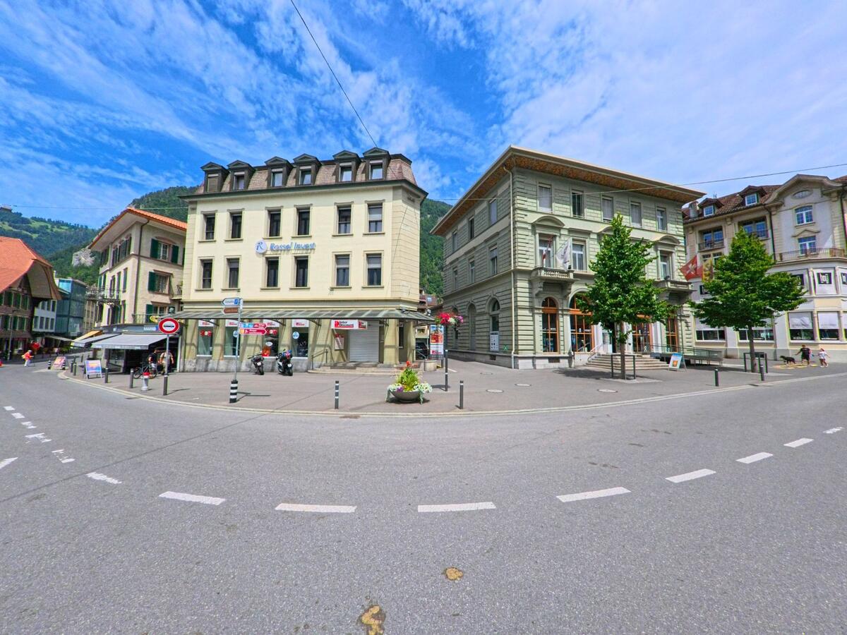 Im Zentrum von Interlaken (3800, Kanton Bern) treffen sich mehrere Strassen vor klassischen Stadthaeusern mit Ladengeschaeften im Erdgeschoss und dekorativen Fassaden.