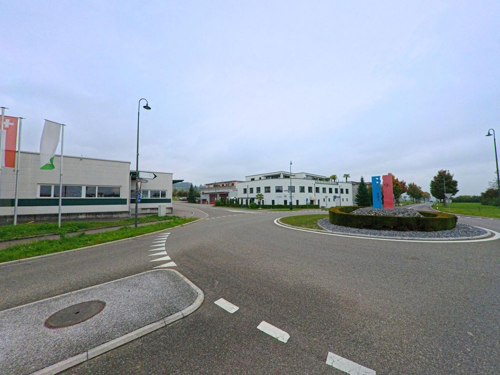 Am Kreisel in Jonen (8916, Kanton Aargau) stehen moderne Gewerbegebäude mit gepflegten Grünanlagen und Fahnenmasten entlang der Zufahrtsstrasse.