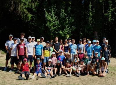 Die Kinder und Jugendlichen der JuBla Schötz aus Schötz (6247, Kanton Luzern) posieren gemeinsam auf einer Wiese vor einem bewaldeten Hintergrund.