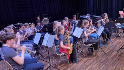 Die Jugendmusik Allegro Region Baden (5400, Kanton Aargau) probt auf einer Bühne, während junge Musikerinnen und Musiker konzentriert ihre Instrumente spielen.
