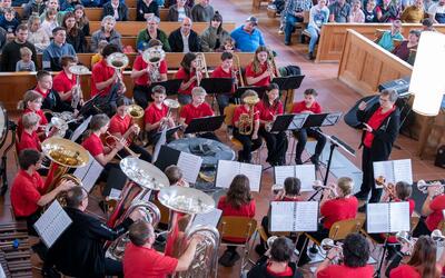 In einer Kirche musizieren Jugendliche in Rehetobel (9038, Kanton Appenzell Ausserrhoden) gemeinsam mit Blasinstrumenten unter der Leitung einer Dirigentin.