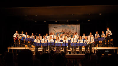 Die Jugendmusik Uzwil aus Uzwil (9249, Kanton St. Gallen) steht auf der Bühne und präsentiert ein Konzert mit Blasinstrumenten vor Publikum.