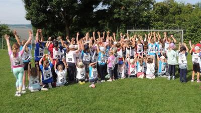 Die Kinder der Jugi Lunkhofen (Kanton Aargau) stehen auf einem Sportfeld und recken jubelnd die Arme in die Luft nach einem Wettkampf.