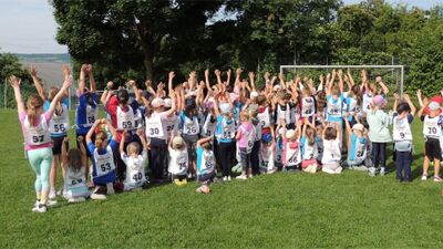 Die Kinder der Jugi Lunkhofen (Kanton Aargau) stehen auf einem Sportfeld und recken jubelnd die Arme in die Luft nach einem Wettkampf.