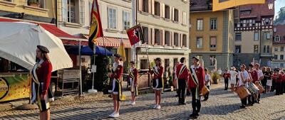 In Burgdorf (3400, Kanton Bern) marschiert eine Gruppe in Uniform mit Fahnen und Trommeln durch eine Altstadtstrasse.