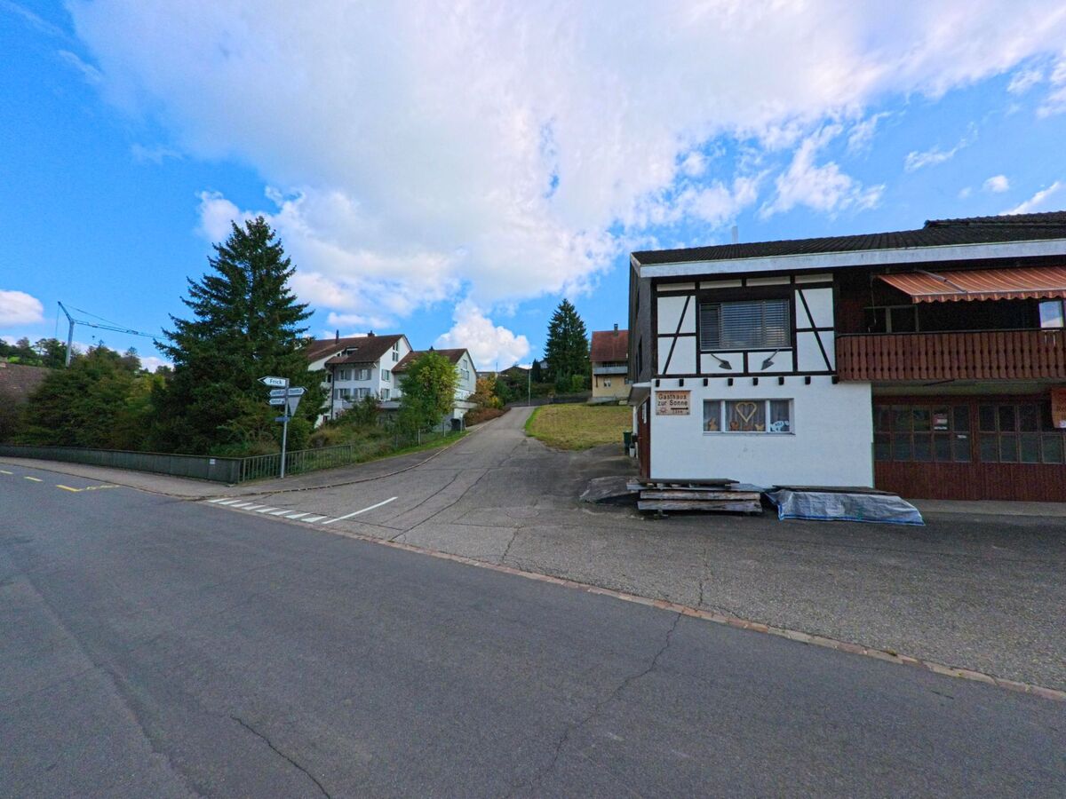 Am Strassenrand in Kaisten (5082, Kanton Aargau) steht das Gasthaus zur Sonne mit Fachwerkfassade, daneben führt eine ansteigende Nebenstrasse zu Wohnhäusern hinauf.