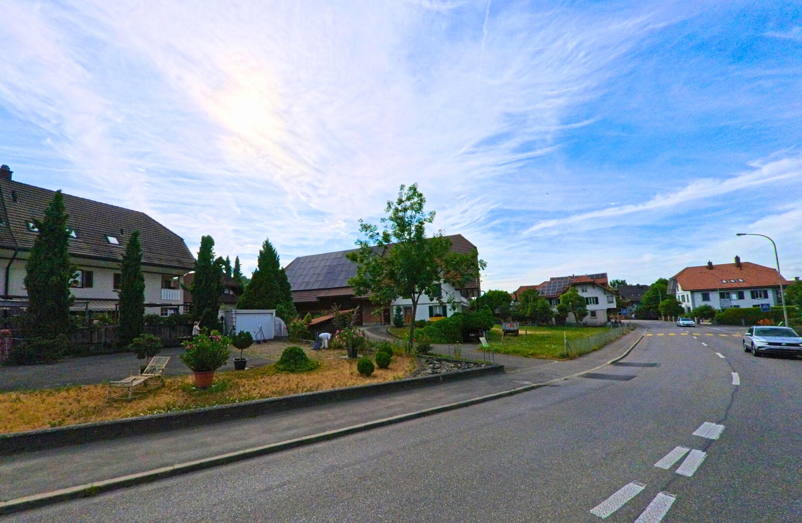 In einem Wohnquartier von Kallnach (3283 im Kanton Bern) reihen sich gepflegte Einfamilienhäuser entlang einer breiten, ruhig wirkenden Strasse.