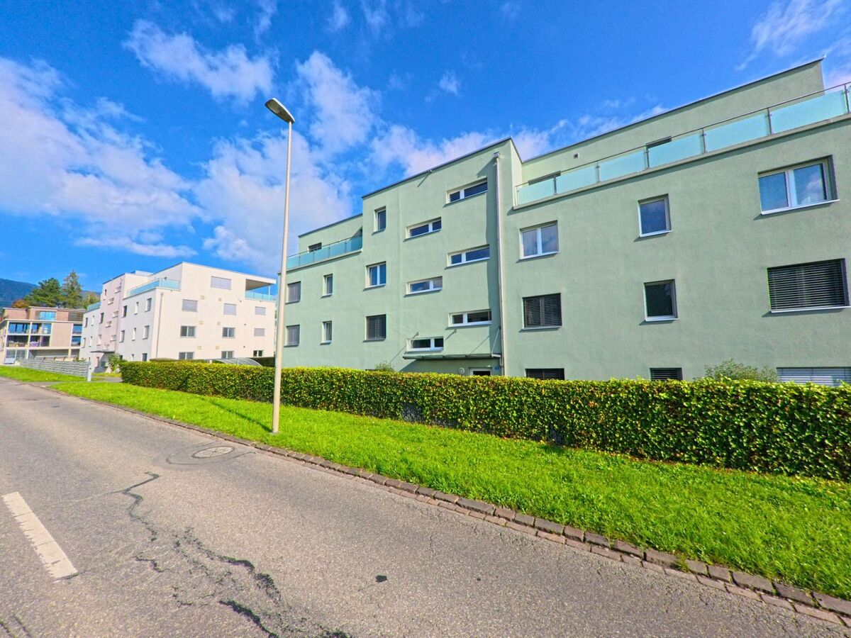 Eine Reihe moderner Wohnhaeuser in Kaltbrunn (8722, Kanton St. Gallen) steht entlang einer ruhigen Strasse mit gepflegter Hecke und grasbewachsenem Randstreifen.