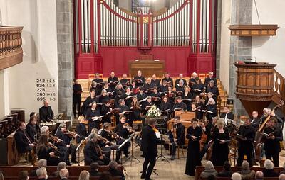In Chur (7000, Kanton Graubünden) tritt ein Kammerchor gemeinsam mit einem Orchester in einer Kirche vor einer grossen Orgel auf.