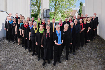 Gruppenfoto des Kath. Kirchenchors Langendorf 4513 im Kanton Schaffhausen mit Sängerinnen und Sängern in schwarzer Kleidung vor moderner Architektur bei Tageslicht.