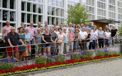 Mitglieder eines Kirchenchors stehen gemeinsam vor einem Gebaeude und posieren fuer ein Gruppenfoto in Oberuzwil (9242, Kanton St Gallen).