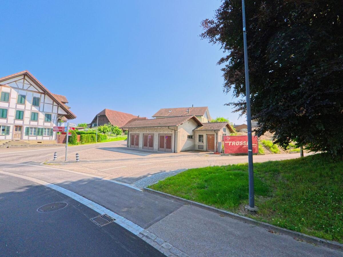 In Kernenried (3309, Kanton Bern) sind zwei Gebäude an einer Straßenecke zu sehen, eines mit einem traditionellen Fachwerkstil und das andere in renovierter Form.
