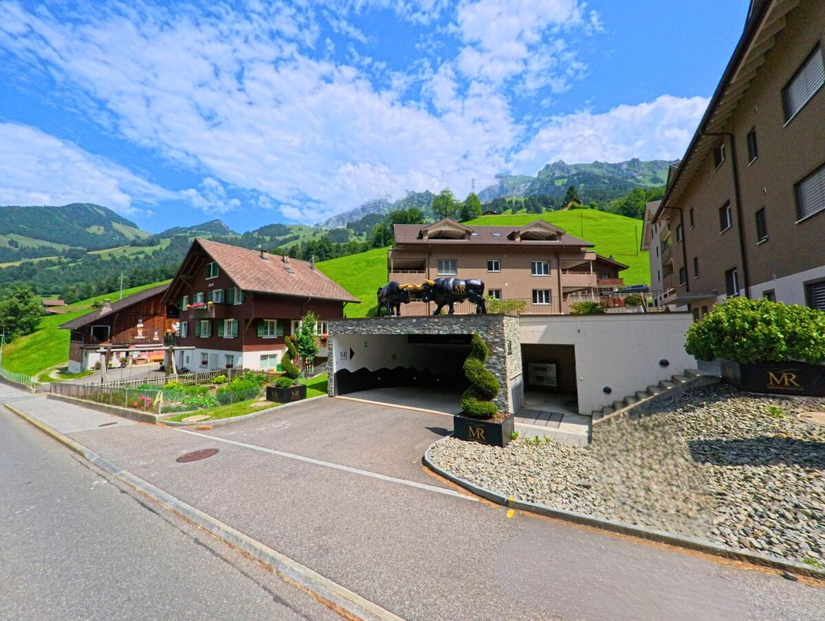 In Kerns (6067, Kanton Obwalden) stehen traditionelle und moderne Wohnbauten nebeneinander, wobei auf einem Garagendach eine auffaellige schwarze Stierfigur platziert ist.