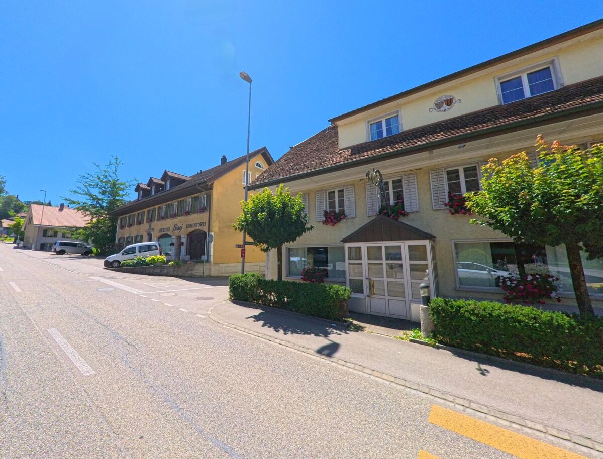 In Kestenholz (4703, Kanton Solothurn) säumen Gasthausgebäude mit Fensterläden und Blumenkästen eine leicht ansteigende Strasse im Dorfzentrum.