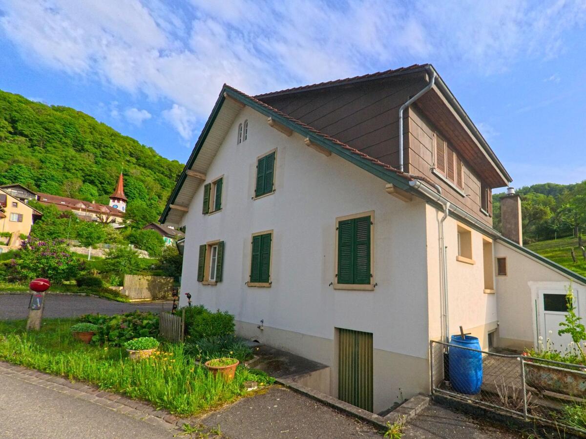 In einem Wohnquartier von Kienberg (4468, Kanton Solothurn) steht ein helles Einfamilienhaus mit Blick auf die Dorfkirche am bewaldeten Hang.