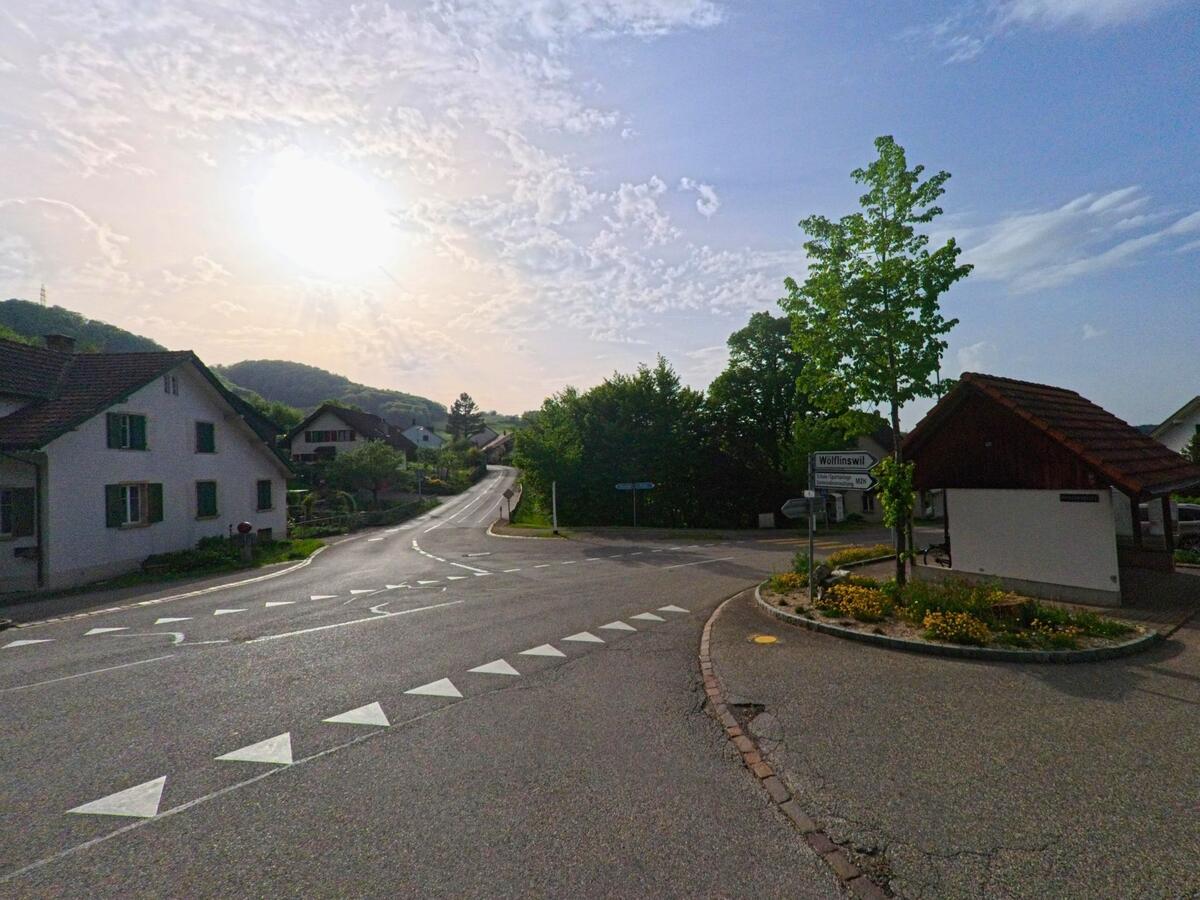 In Kienberg (4468, Kanton Solothurn) zeigt sich die Ausfahrt Richtung Wölflinswil bei tiefstehender Sonne mit Blick auf die sanfte Hügellandschaft.