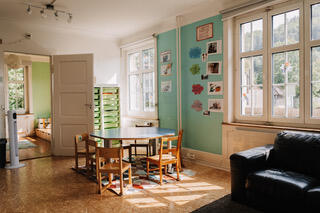 In Sissach (4450, Kanton Baselland) ist ein heller Raum der Kindertagesstaette Zwaergehuus mit Kindertischen, Spielsachen und grossen Fenstern liebevoll eingerichtet.