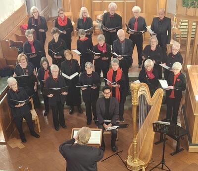 Der Kirchenchor singt unter der Leitung einer Dirigentin mit Harfenbegleitung während eines Konzerts in der Kirche von Weiningen (8104, Kanton Zürich).