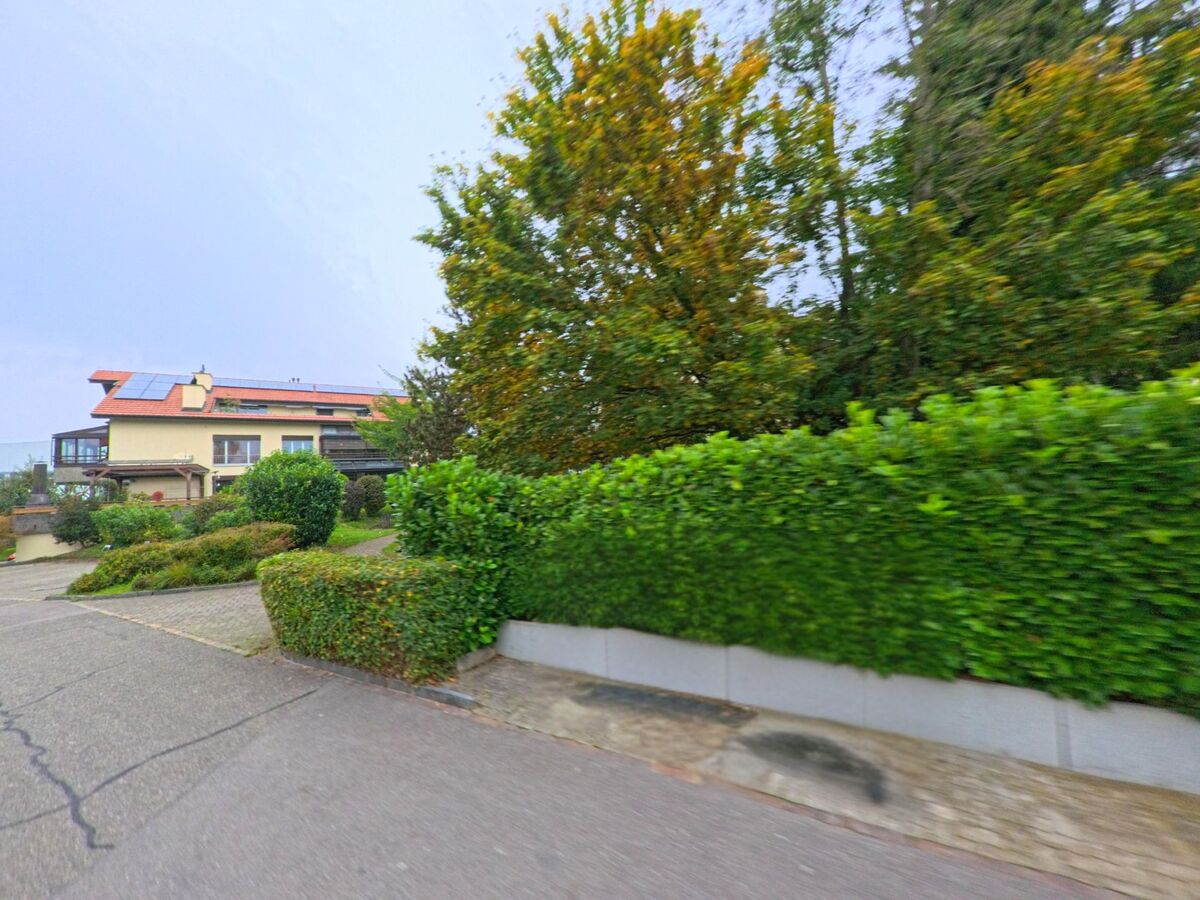 Ein Wohnhaus mit Solarpanels auf dem Dach steht in Klingnau (5313, Kanton Aargau) hinter gepflegten Hecken und Bäumen an einer Nebenstrasse.