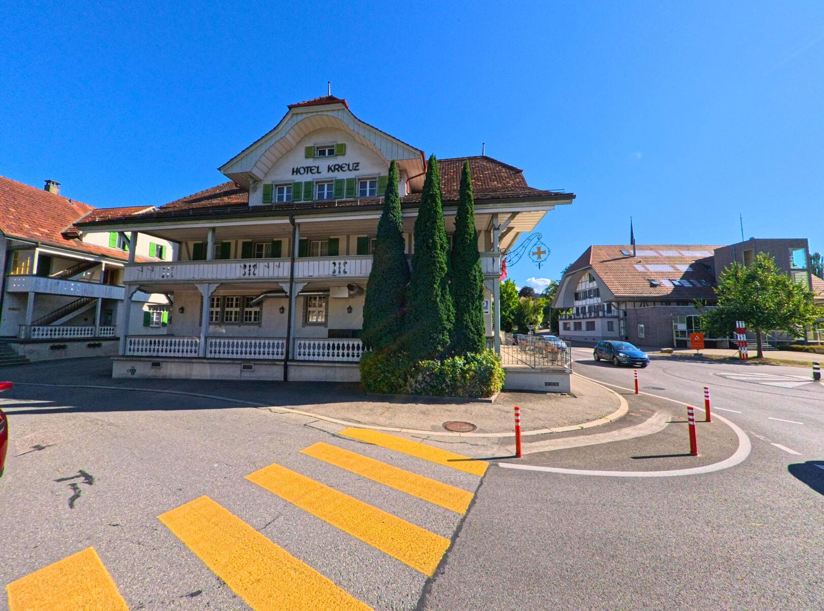 In Konolfingen (PLZ 3510, Kanton Bern) steht an einer Strassenkreuzung das traditionelle Hotel Kreuz mit markanter Holzfassade und begrüntem Vorplatz.