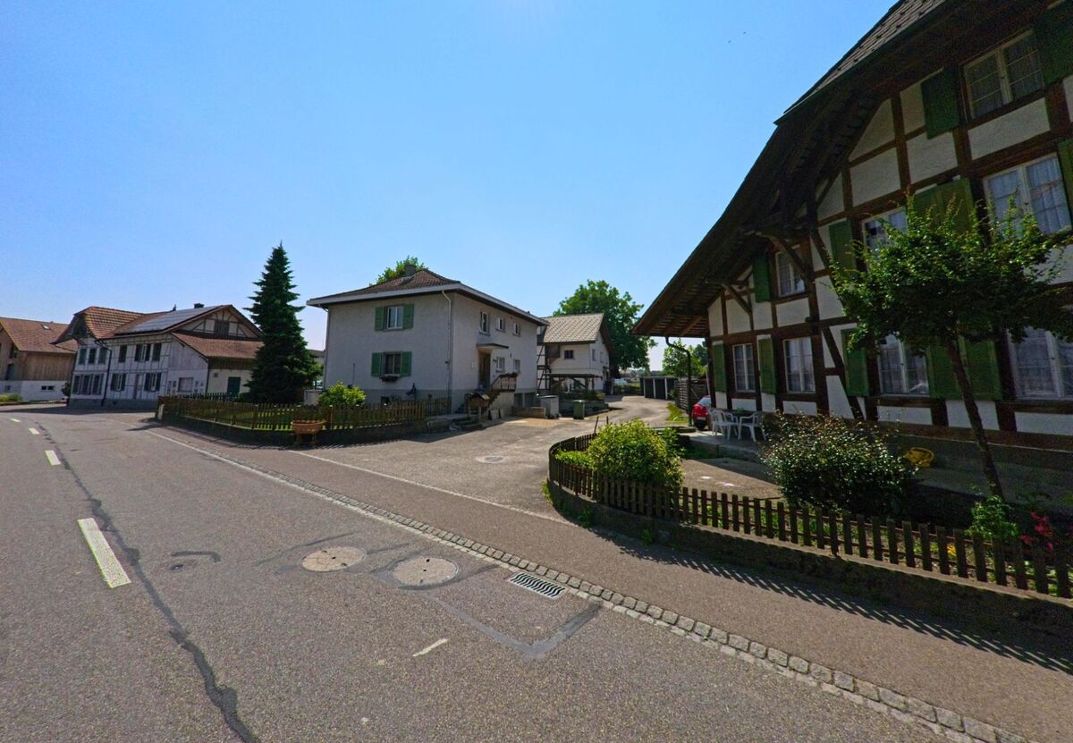 In Koppigen (3425, Kanton Bern) prägen ein Mix aus traditionellen Fachwerkhäusern und schlichten Wohnbauten das ruhige Ortsbild entlang einer Nebenstrasse.