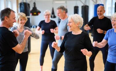 In einem Trainingsraum in Aarau (5000, Kanton Aargau) übt eine Gruppe älterer Frauen und Männer gemeinsam Bewegungen zur Selbstverteidigung.