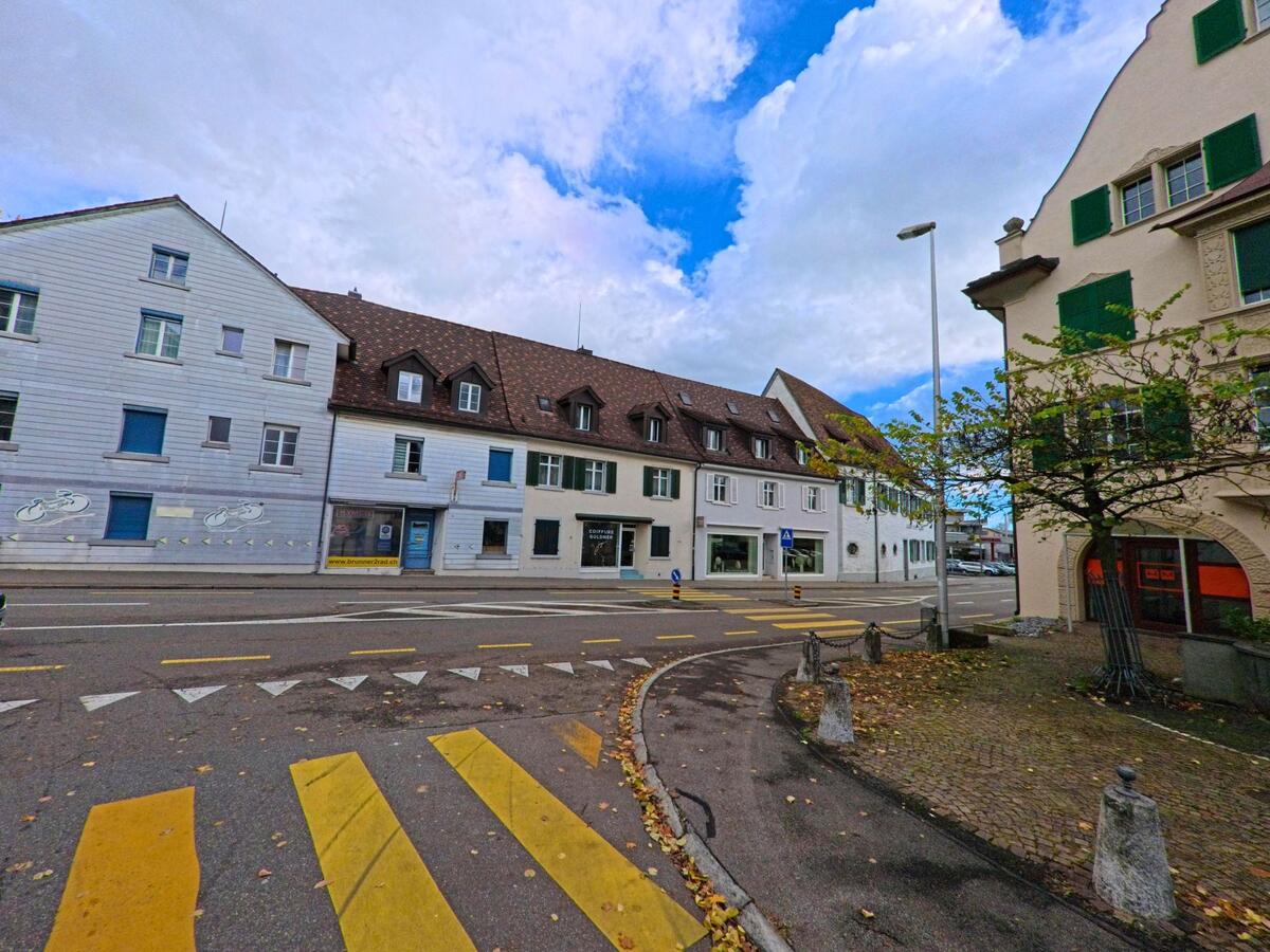 Ein gelber Fussgängerstreifen führt in Kreuzlingen (8280, Kanton Thurgau) über eine Quartierstrasse vor einer Reihe von Häusern mit grünen Fensterläden.