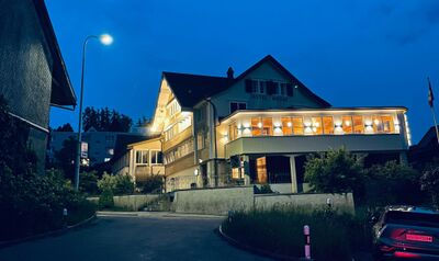 In Wolfhalden (9427, Kanton Appenzell Ausserrhoden) leuchtet das Hotel Krone am Abend warm beleuchtet unter dem dunklen Himmel, mit grossen Fenstern und traditioneller Fassade.